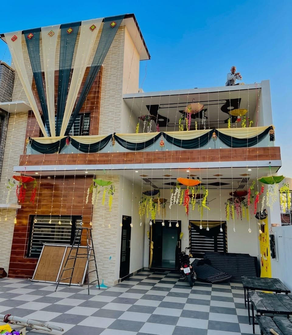 House exterior decorated with black and yellow drapes, hanging colourful umbrellas and fairy-light strings for a celebration
